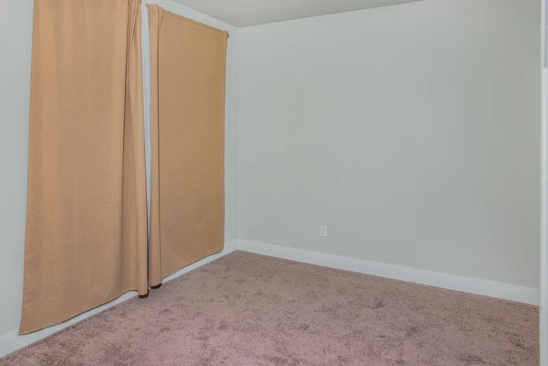 Bedroom with soft carpet, pale walls and floor-length curtains over a large window