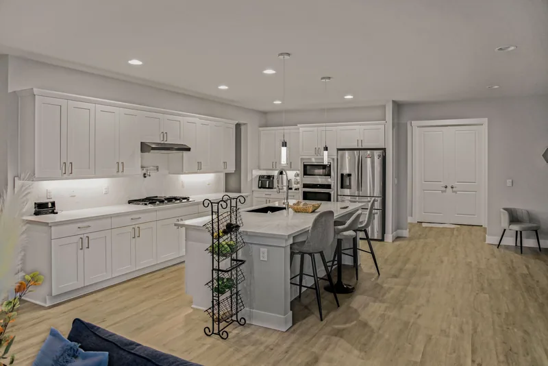 Kitchen with white shaker cabinets, a large island with barstools, stainless-steel appliances and pendant lights