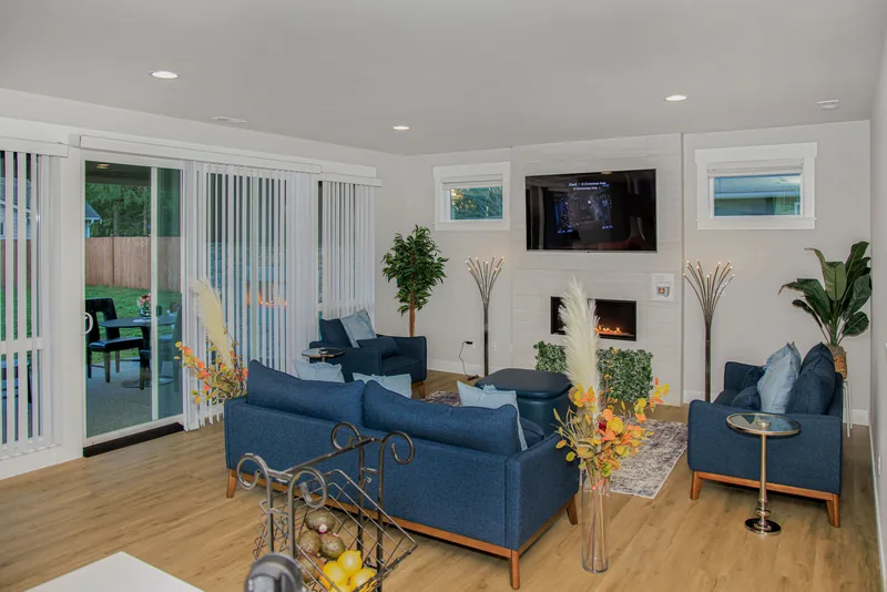 Bright living room with navy seating, an electric fireplace and TV, and large sliding glass doors to the patio