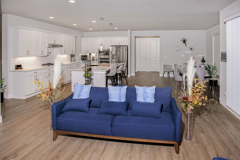 Open-plan living area looking past a navy sofa toward the white kitchen island and the dining table